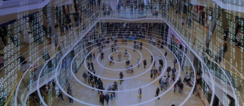 Radio waves spreading out from a mobile phone in a shopping mall with matrix style data layered on top.