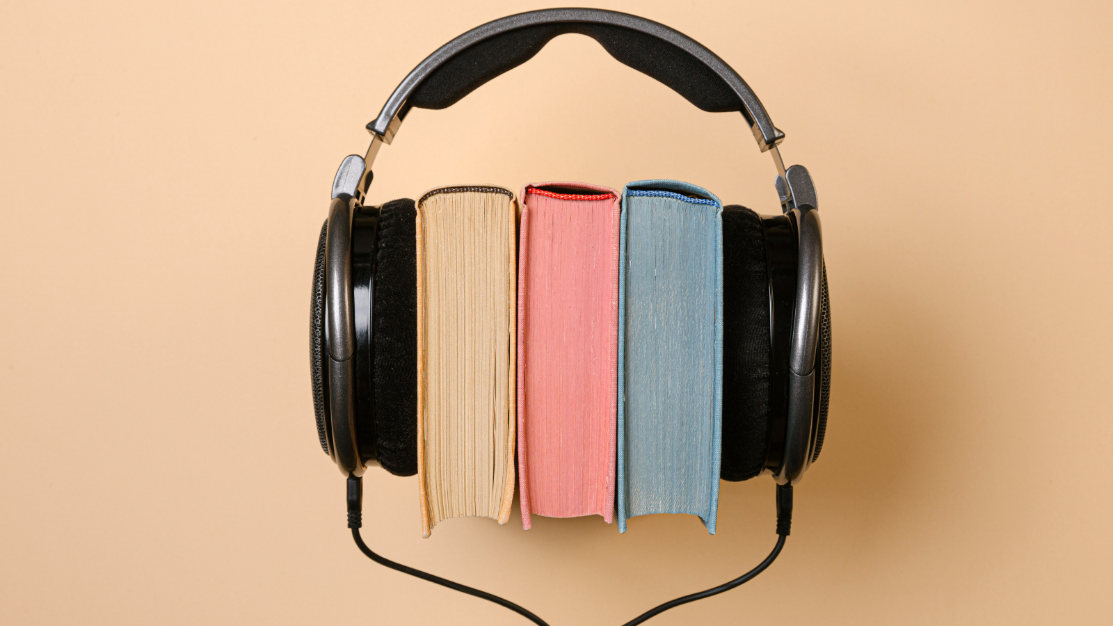 Black-corded headphone, with three books on end where a persons head would normally be when using the headphones.