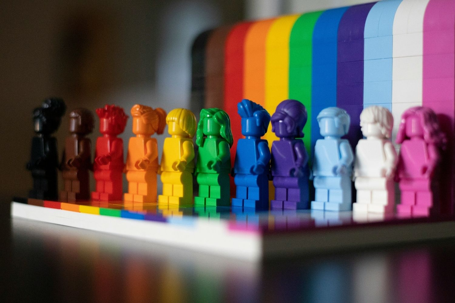 Lego figures are arranged in colour order for the Progress Pride flag (extended LGBTQ+ flag that includes the colours for the trans flag and people of colour).