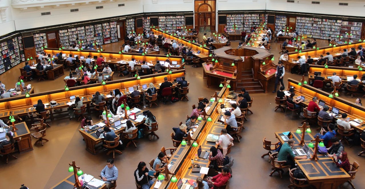 Overhead view of people working at desks in a library.