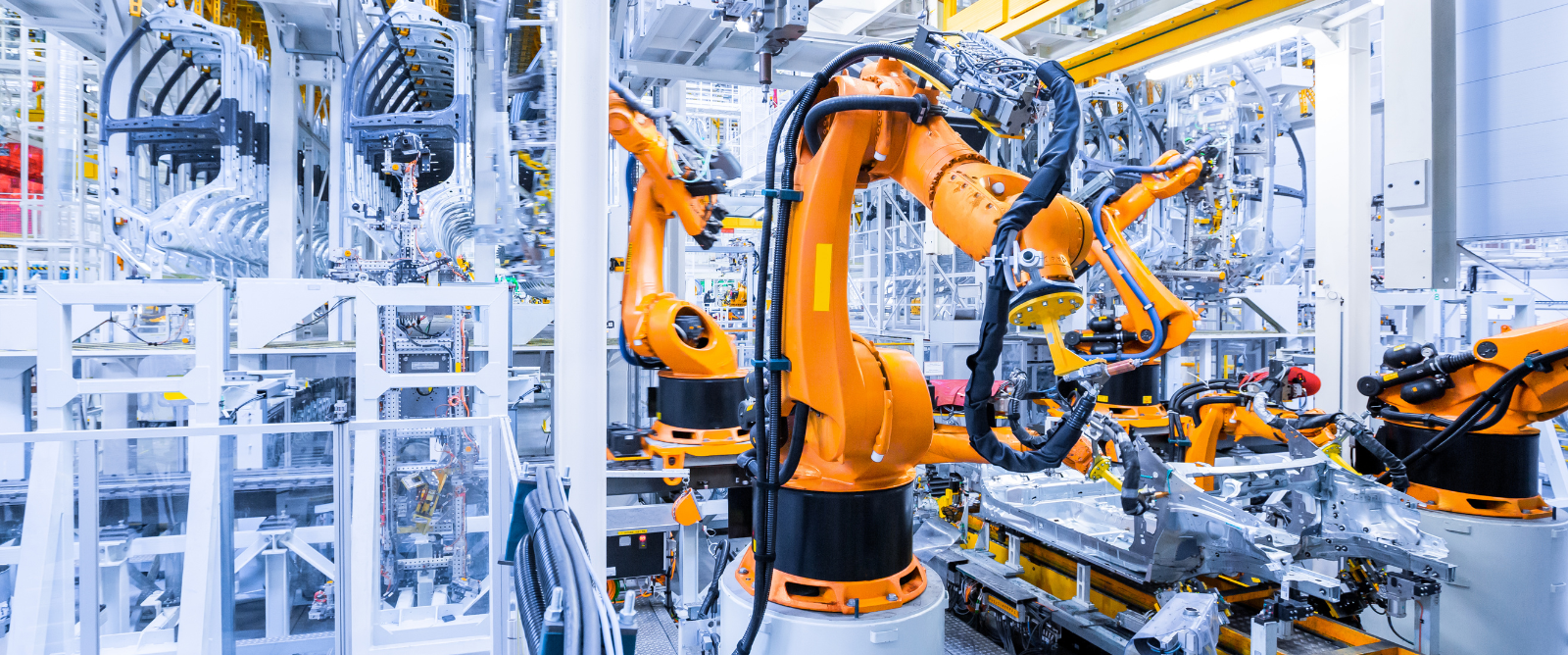 Photo inside car factory, showing robotic construction