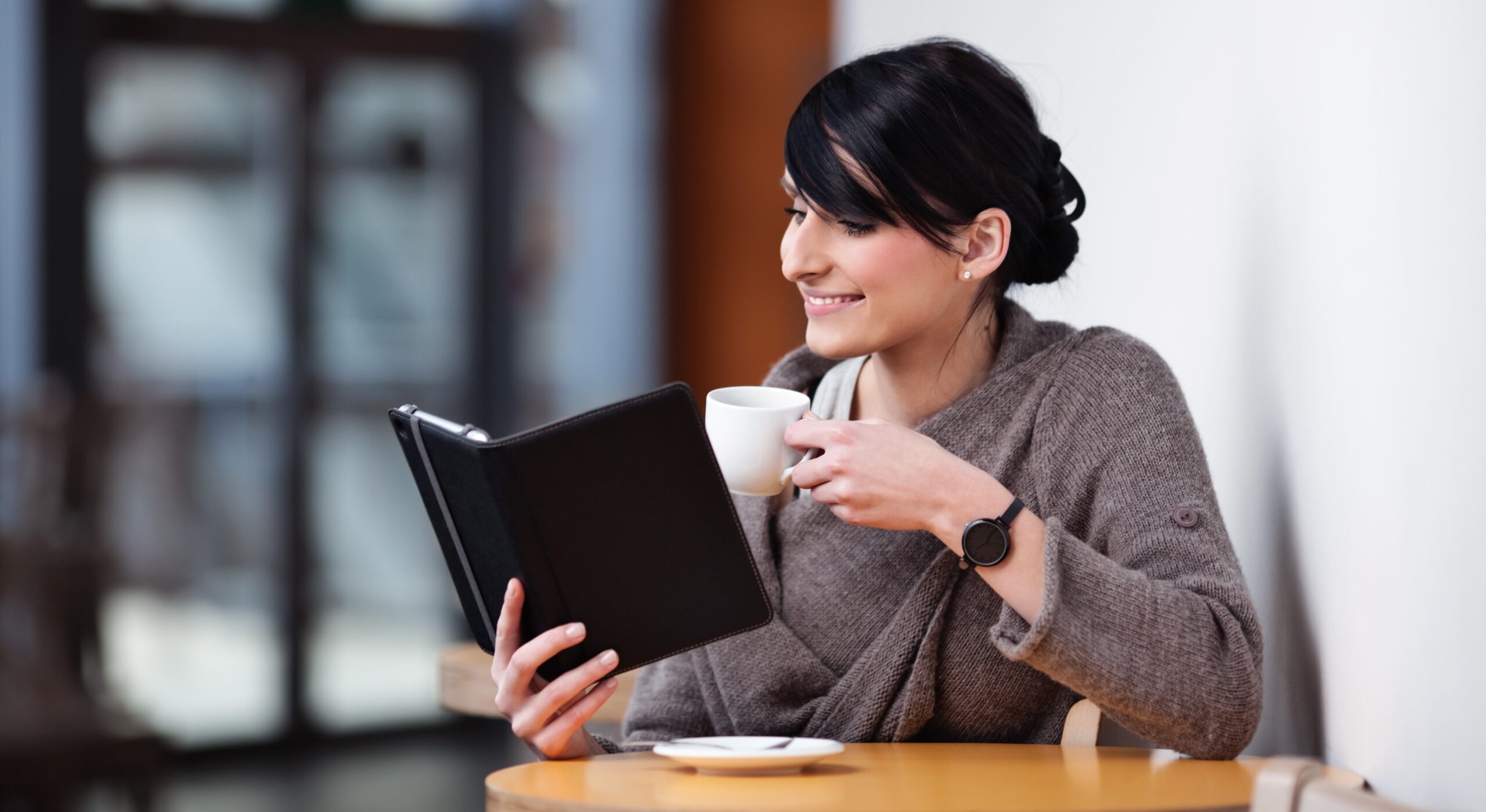 Person in a cafe reading an ebook and drinking coffee