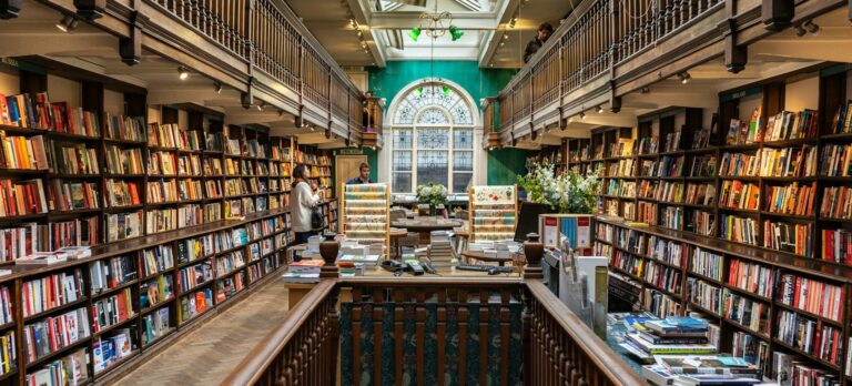 Photo inside London's Daunt Books, a long galleried room lined with bookshelves.