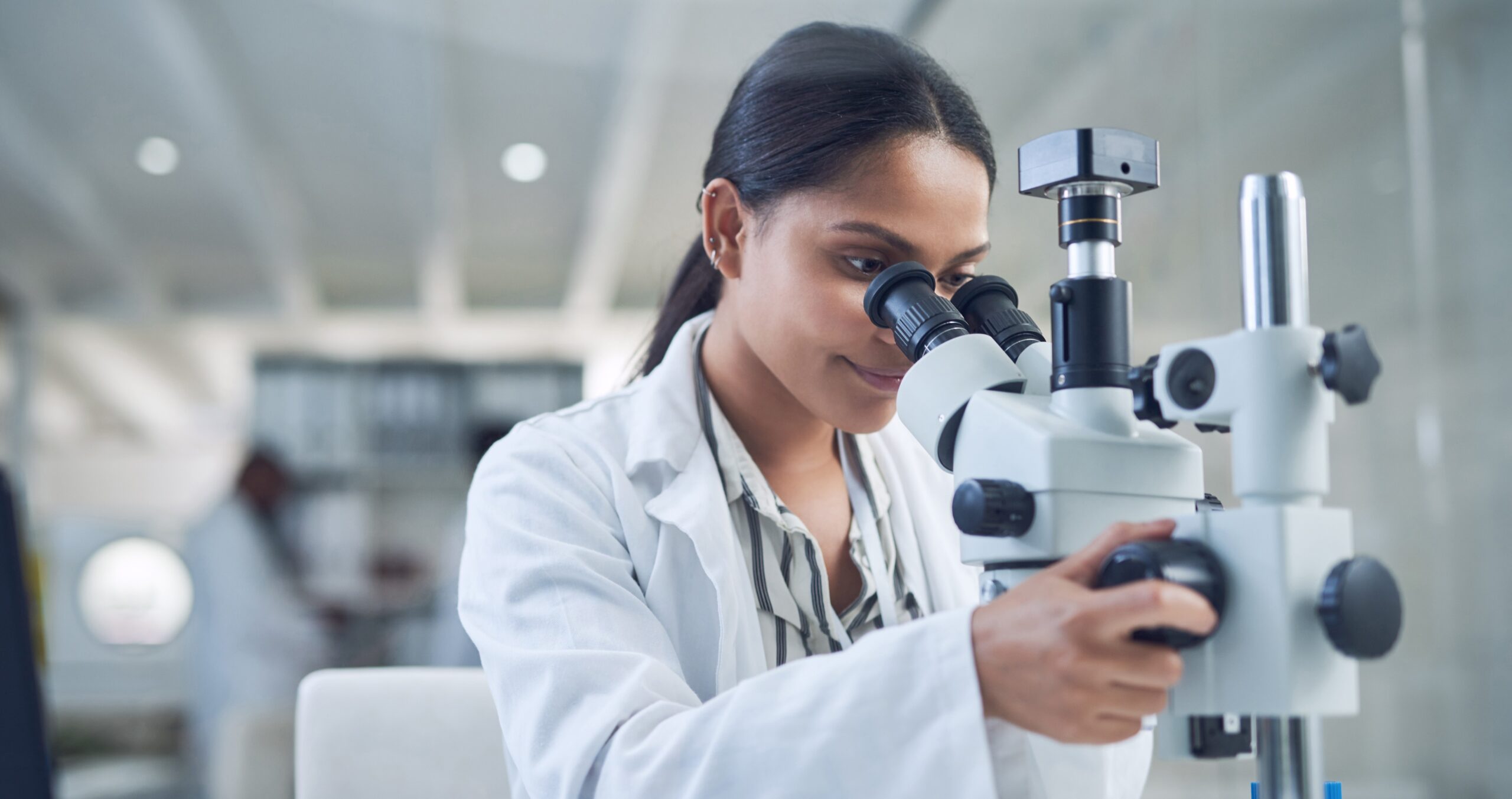 Researcher wearing a lab coat using a microscope