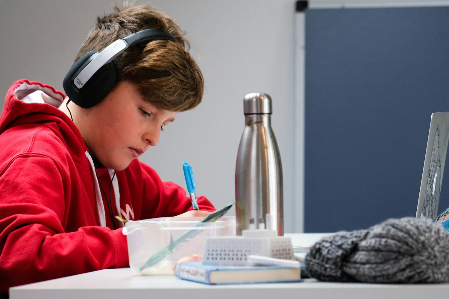 A boy is studying with his headphones on.