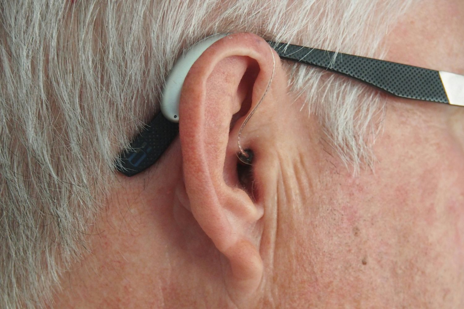 Side shot of an older person's ear with a hearing aid in it.